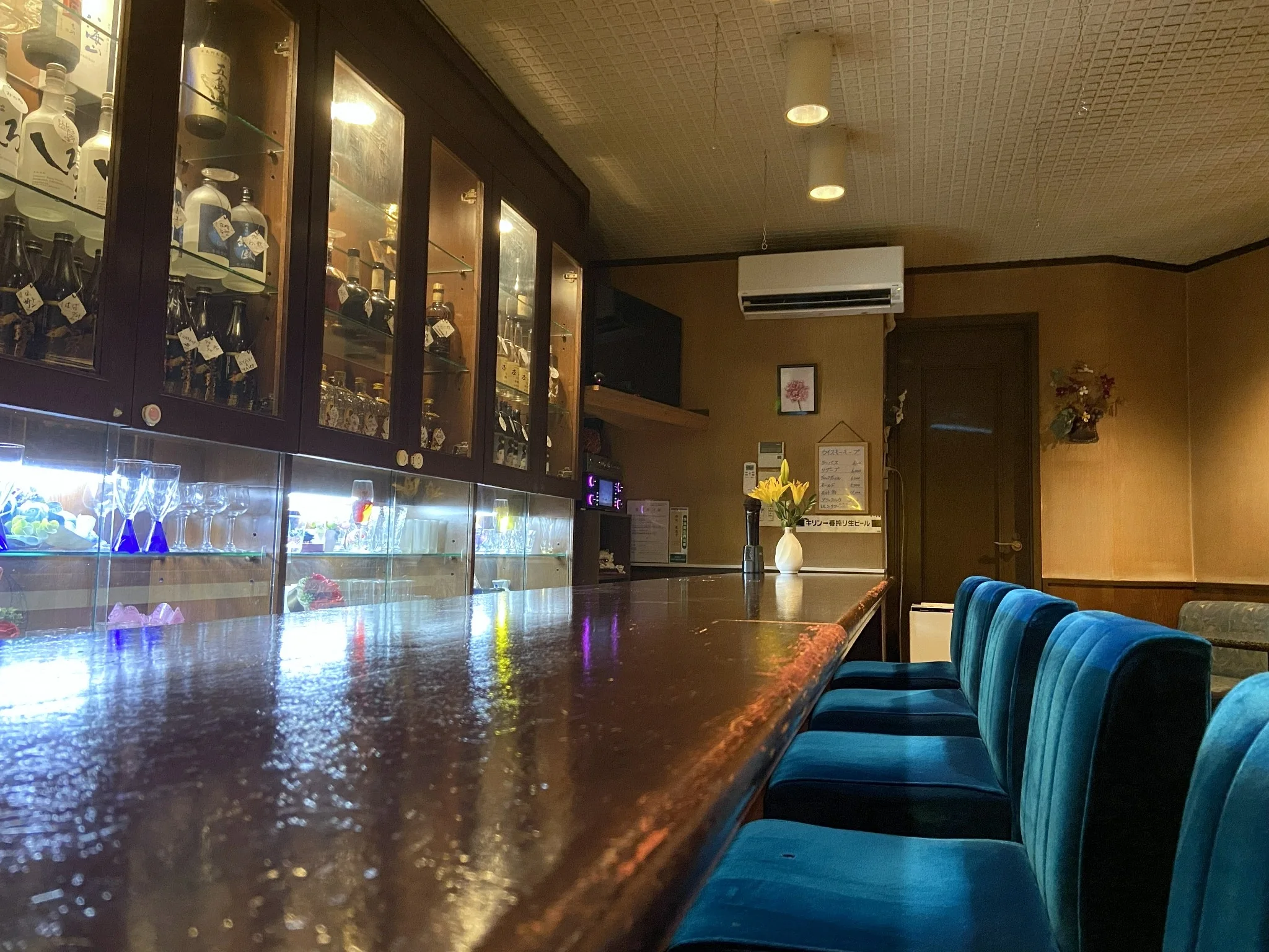 木目のカウンターとピンクの椅子が並ぶ、暖色照明の店内